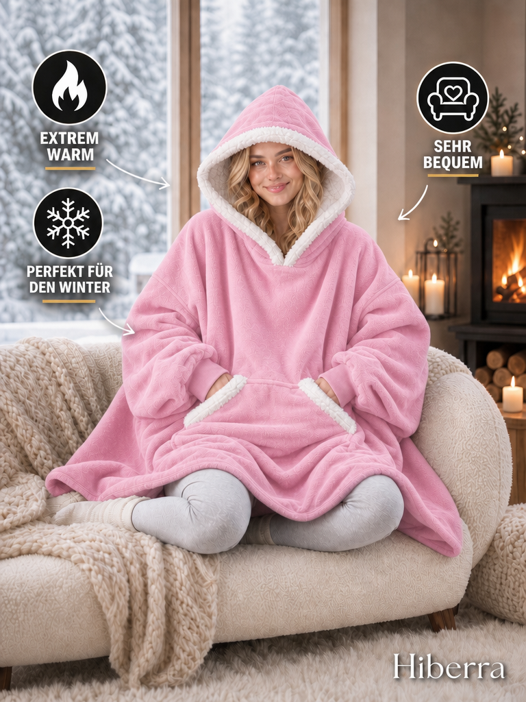 Frau im rosa Hiberra Kuschelhoodie auf dem Sofa – extra warm, sehr bequem, perfekt für den Winter – Farbe Rosa