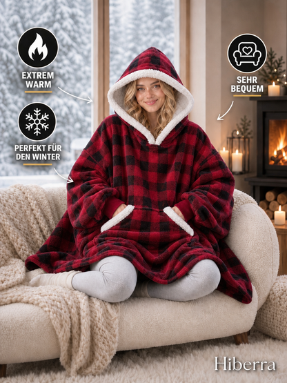 Frau im Hiberra Kuschelhoodie in Rot kariert auf dem Sofa – extra warm, sehr bequem, perfekt für den Winter – Farbe Rot kariert