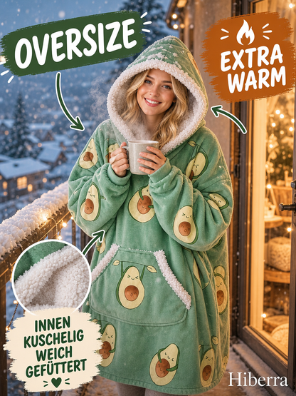Frau steht auf dem Balkon im Hiberra Kuschelhoodie in Avocado-Print und hält eine Tasse – Farbe Avocado-Print