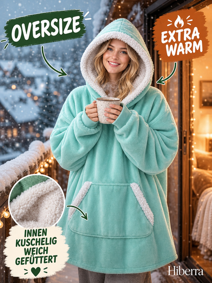Frau steht auf dem Balkon im mintgrünen Hiberra Kuschelhoodie und hält eine Tasse – Farbe Mintgrün