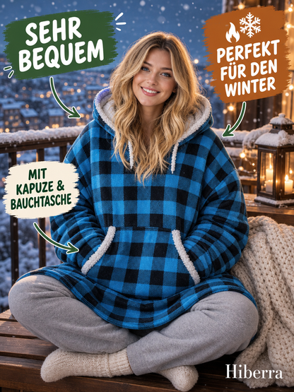 Frau sitzt auf dem Balkon im Hiberra Kuschelhoodie in Blau kariert – Farbe Blau kariert