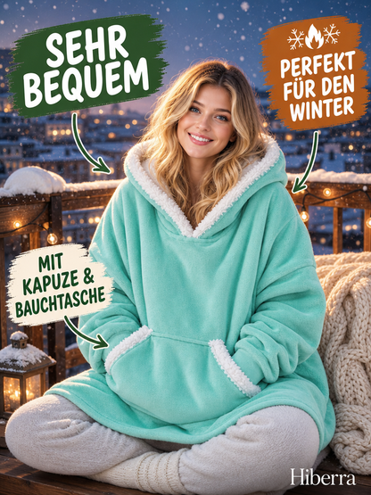 Frau sitzt auf dem Balkon im mintgrünen Hiberra Kuschelhoodie – Farbe Mintgrün