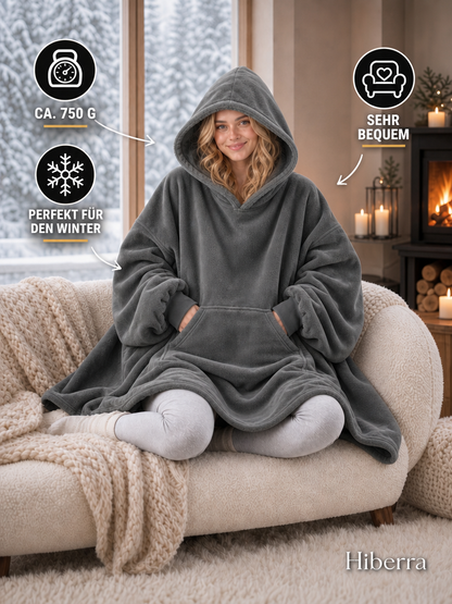 Frau in der dunkelgrauen Hiberra Hoodie-Decke auf dem Sofa, ca. 750 g – Farbe Dunkelgrau