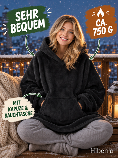 Frau in der schwarzen Hiberra Hoodie-Decke sitzt auf dem verschneiten Balkon, ca. 750 g – Farbe Schwarz