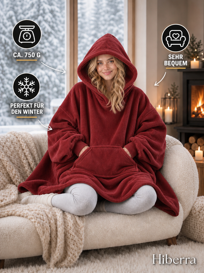 Frau in der weinroten Hiberra Hoodie-Decke auf dem Sofa, ca. 750 g – Farbe Weinrot