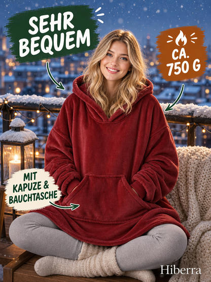 Frau in der weinroten Hiberra Hoodie-Decke sitzt auf dem verschneiten Balkon, ca. 750 g – Farbe Weinrot