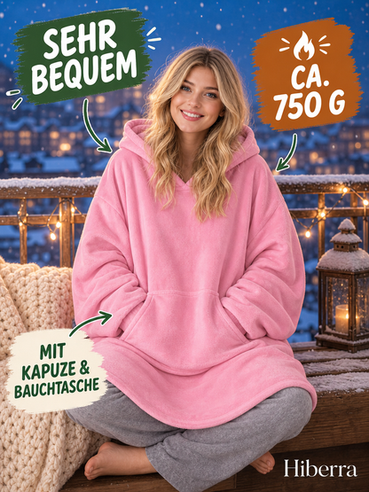 Frau in der rosa Hiberra Hoodie-Decke sitzt auf dem verschneiten Balkon, ca. 750 g – Farbe Rosa