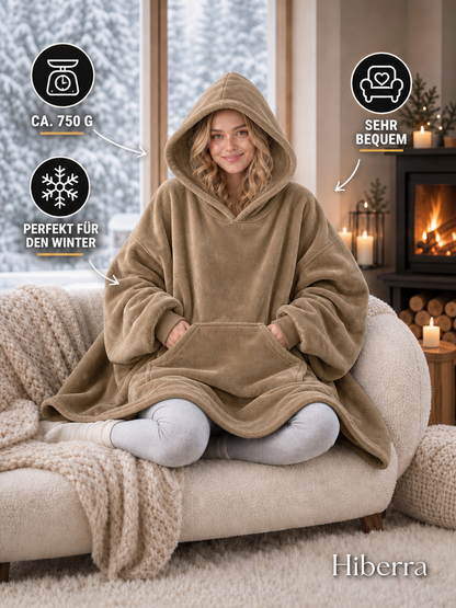 Frau in der khakifarbenen Hiberra Hoodie-Decke auf dem Sofa, ca. 750 g – Farbe Khaki