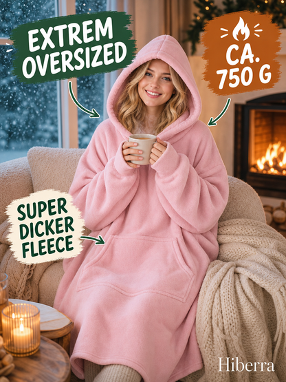Frau in der puderrosa Hiberra Hoodie-Decke mit Tee am Kamin, ca. 750 g – Farbe Puderrosa