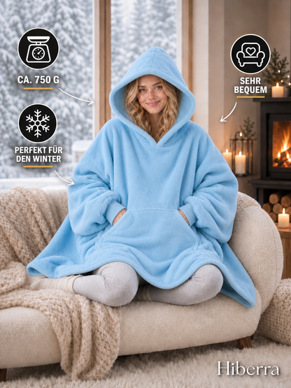 Frau in der hellblauen Hiberra Hoodie-Decke auf dem Sofa, ca. 750 g – Farbe Hellblau