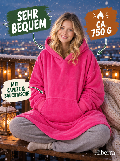 Frau in der pinken Hiberra Hoodie-Decke sitzt auf dem verschneiten Balkon, ca. 750 g – Farbe Pink